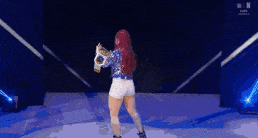 a woman with red hair is holding a wrestling championship belt .