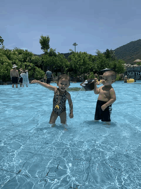 a boy and a girl are playing in a pool that has the word nuith on the wall