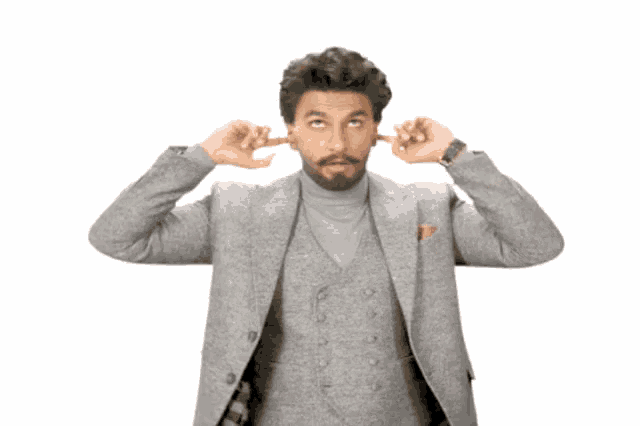 a man covering his ears with his hands while wearing a grey suit