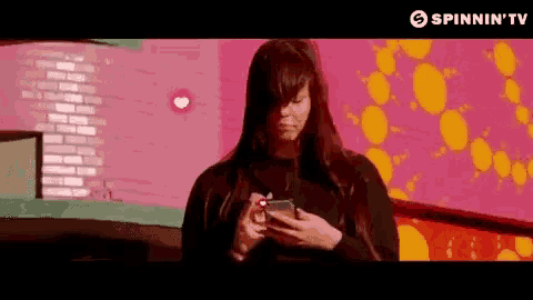 a woman is looking at her phone in front of a colorful background .