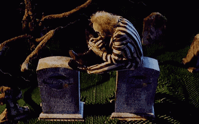 a man in a striped suit sits on a gravestone in a cemetery