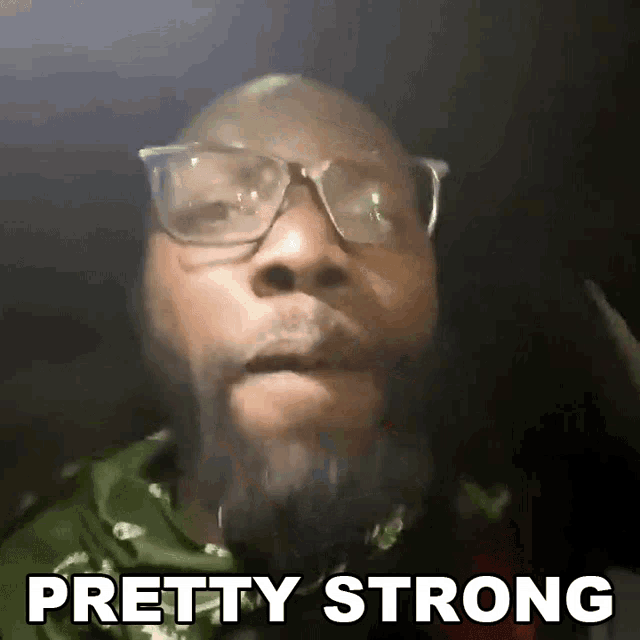 a man with glasses and a beard says " pretty strong " in front of his face