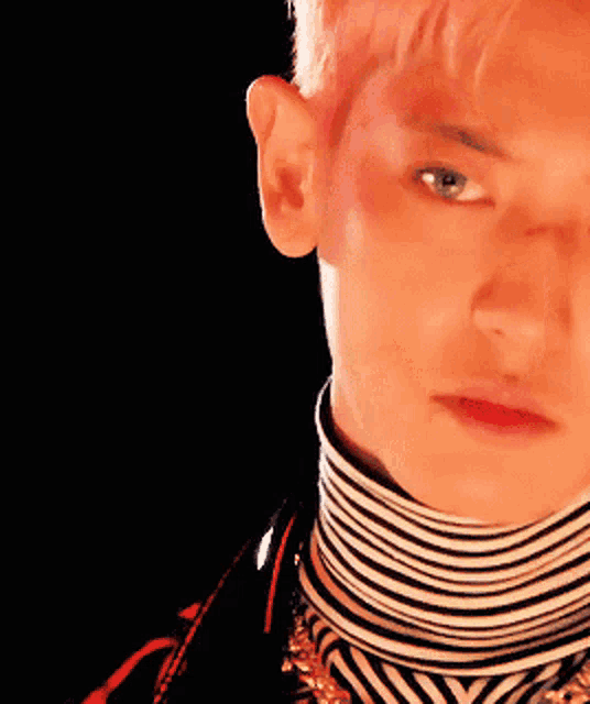 a close up of a man 's face with a striped turtleneck