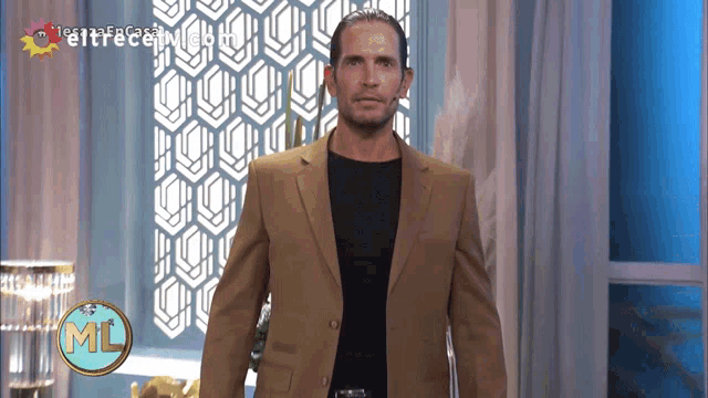 a man in a tan suit is standing in front of a screen that says ml