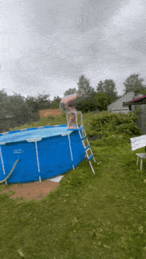 a man jumps into a swimming pool with a ladder