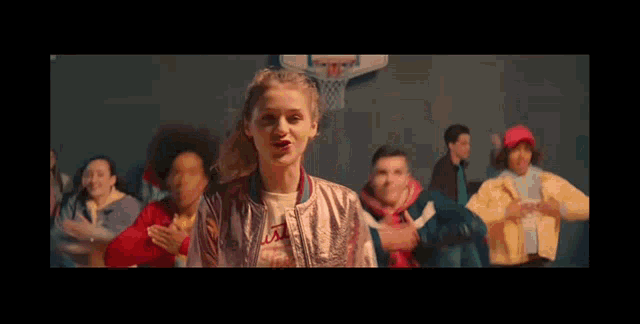 a girl in a pink jacket is standing in front of a group of people .