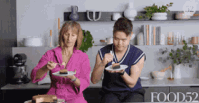 a man and a woman are sitting in a kitchen eating food ..
