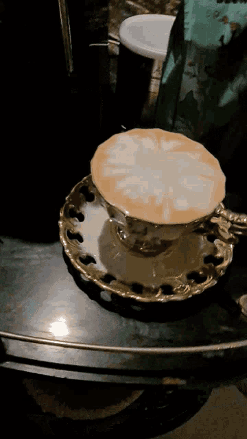 a cup of coffee on a saucer with a flower design