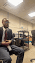a blurry picture of a man in a suit and tie sitting in a chair .