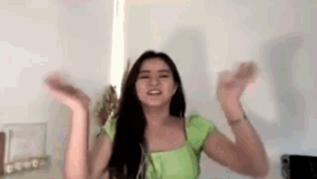 a woman in a green top is dancing with her arms outstretched .