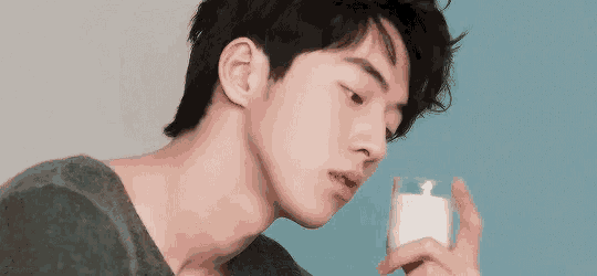 a close up of a young man drinking a glass of milk .
