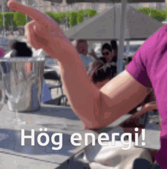 a woman in a purple shirt is sitting at a table with a bucket of champagne and the words hög energi written on the bottom