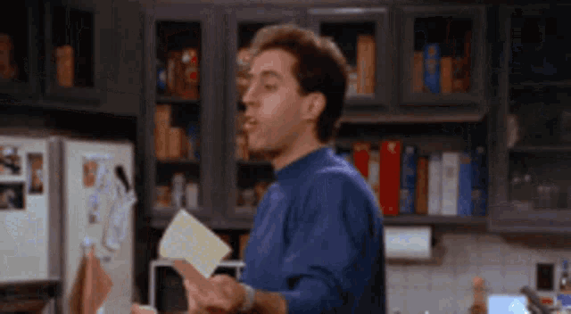 a man in a blue shirt is holding a piece of paper in his hand