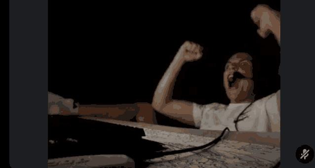 a man wearing headphones is raising his fist in the air in a dark room .