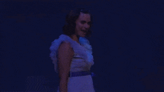 a woman in a white dress with a blue sash is laughing