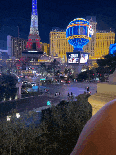 a view of a city at night with a hot air balloon in the foreground and the eiffel tower behind it