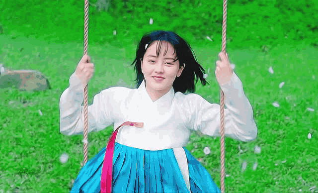 a young woman in a blue and white dress is sitting on a swing .