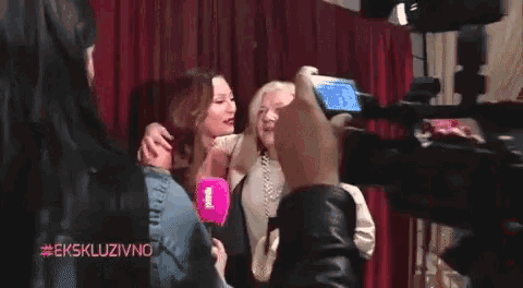 a woman taking a picture of two women with the hashtag #ekskluzivno on the bottom