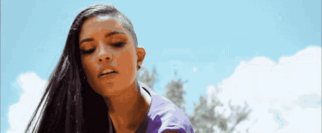 a woman with a shaved head looks down at something