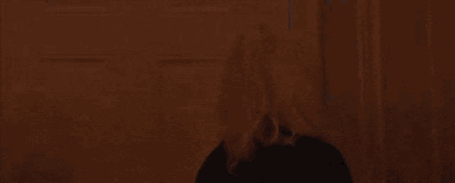 a woman in a black coat is walking through a doorway in a room .