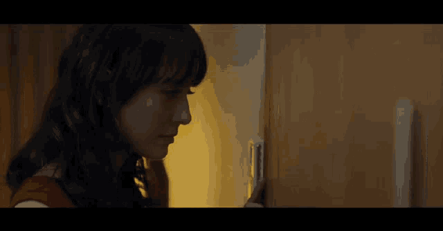 a woman in a red dress is standing in a dark room looking into a door .