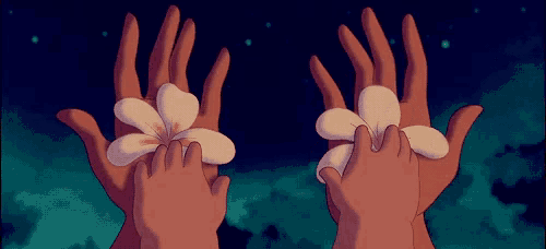a couple of hands holding two flowers in them