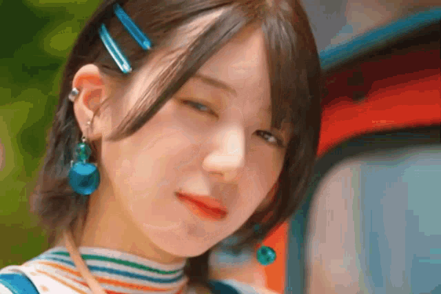a close up of a woman wearing a striped shirt and earrings .