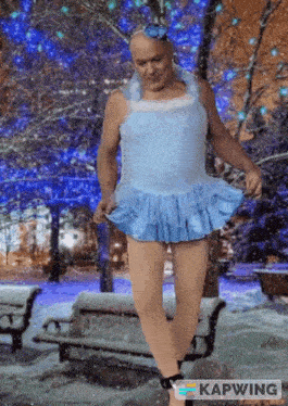 a man in a blue dress is dancing in a snowy park with kapwing in the corner