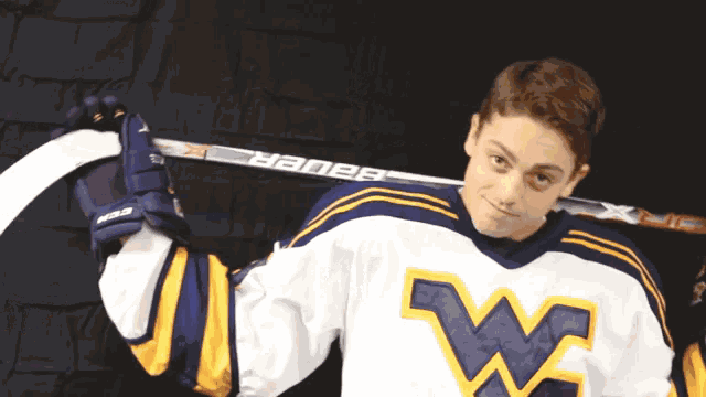 a hockey player holding a bauer hockey stick over his shoulder
