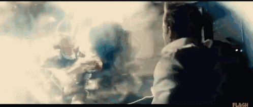 a man in a white jacket is looking out a window at a group of people in a dark room .