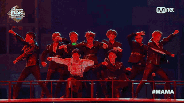 a group of men are dancing in front of a mnet sign