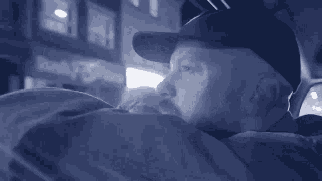 a man wearing a baseball cap is laying down in front of a building