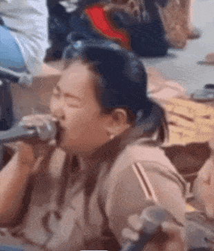a woman is singing into a microphone while holding a spoon in her mouth .