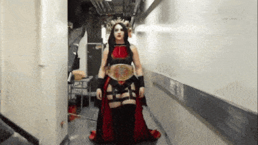 a woman is standing in a hallway wearing a belt that says world heavyweight championship