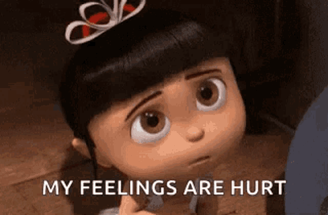 a little girl from despicable me is sitting on the floor with her eyes closed and a bow on her head .