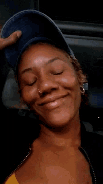 a woman wearing a blue hat and earrings is smiling for the camera