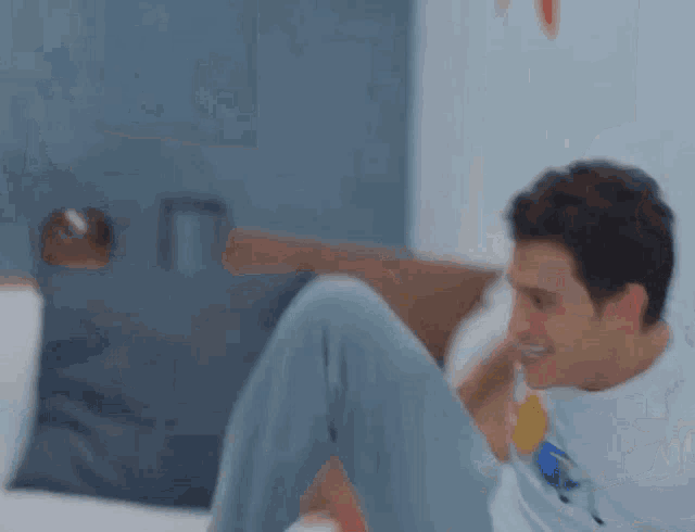 a man is sitting on a bed with his legs crossed and smiling