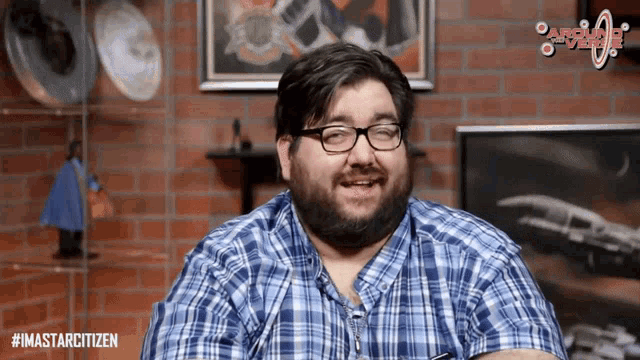 a man wearing glasses and a plaid shirt has the hashtag #imastarcitizen