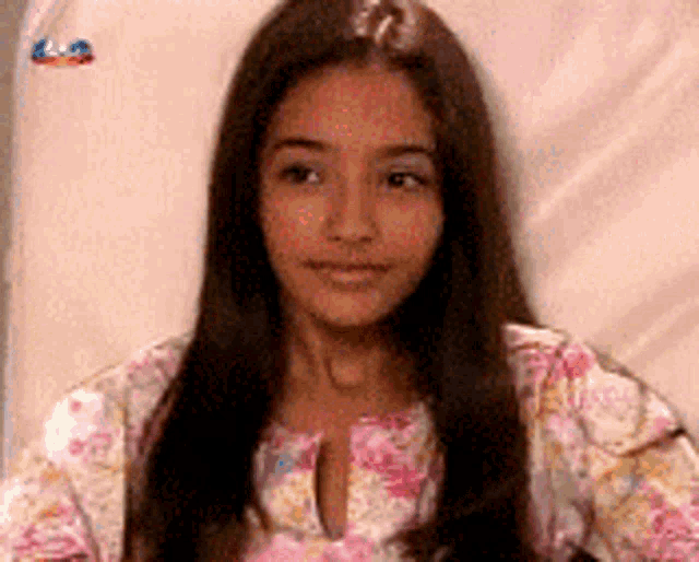 a young girl with long hair is wearing a floral shirt and smiling