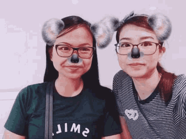 two women wearing koala ears and glasses are standing next to each other .