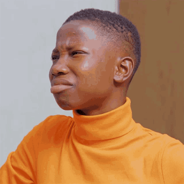 a person wearing an orange turtleneck has the word no on their shirt