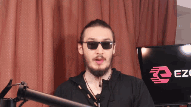 a man wearing sunglasses is standing in front of a screen that says ez
