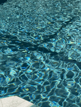 a swimming pool with blue water and a reflection of a person