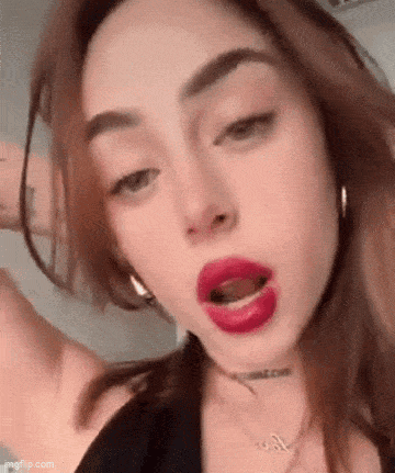 a close up of a woman 's face with red lipstick and earrings .