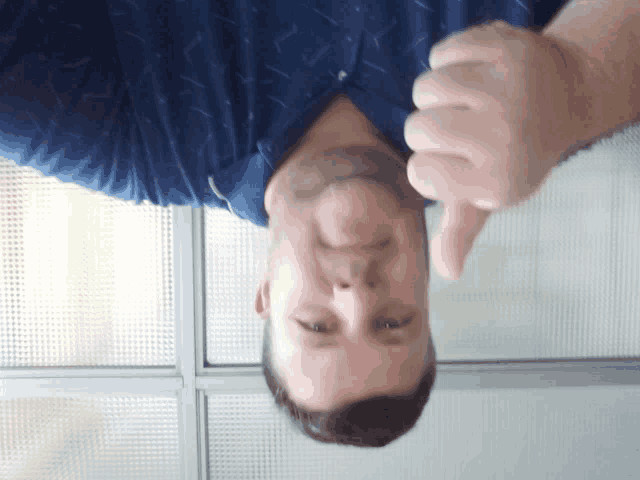 a man in a blue shirt giving a thumbs up sign
