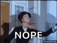 a woman in a top hat is dancing in a room with the word nope written on the screen .