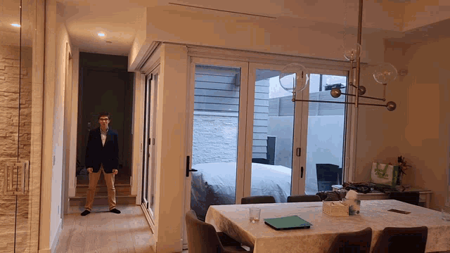 a man in a suit is standing in a room with a table and chairs