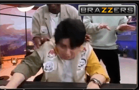 a man is sitting at a desk with a brazzers logo behind him .