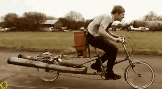 a man riding a bicycle with a large log on the back