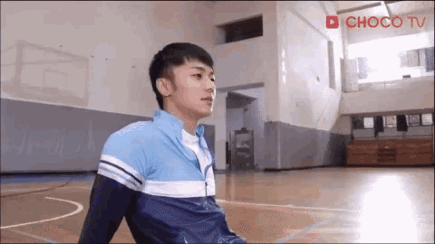 a young man is sitting on the floor of a gym .